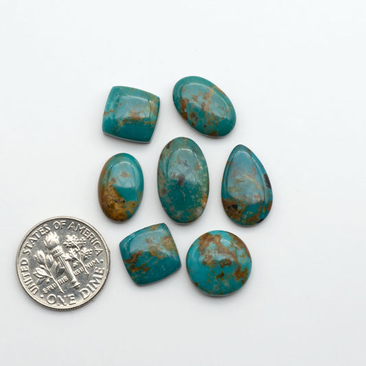 Turquoise stones with a U.S. dime for size comparison on a white background