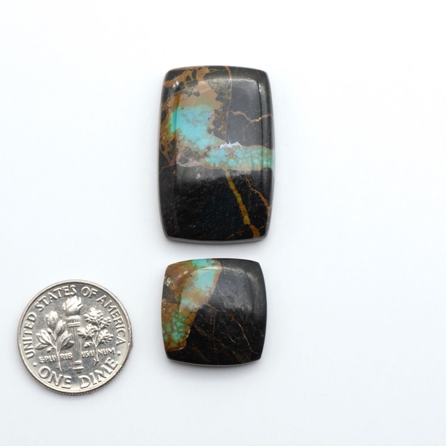 Two turquoise stone cabochons next to a U.S. dime on a white background