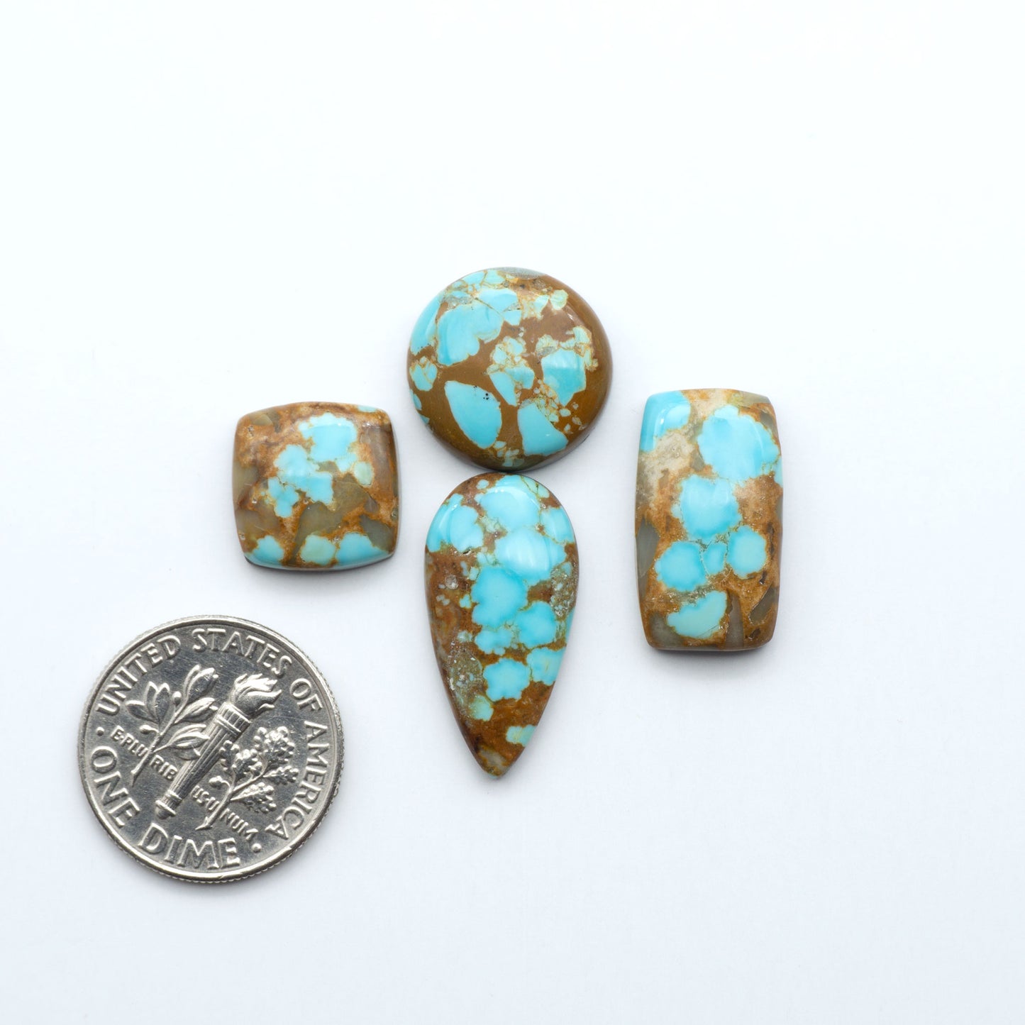 Turquoise stones with a dime for scale on a white background Number 8 Turquoise Cabochons have been selected for their quality and unique appearance. Don't miss the chance to add a one-of-a-kind piece to your collection.