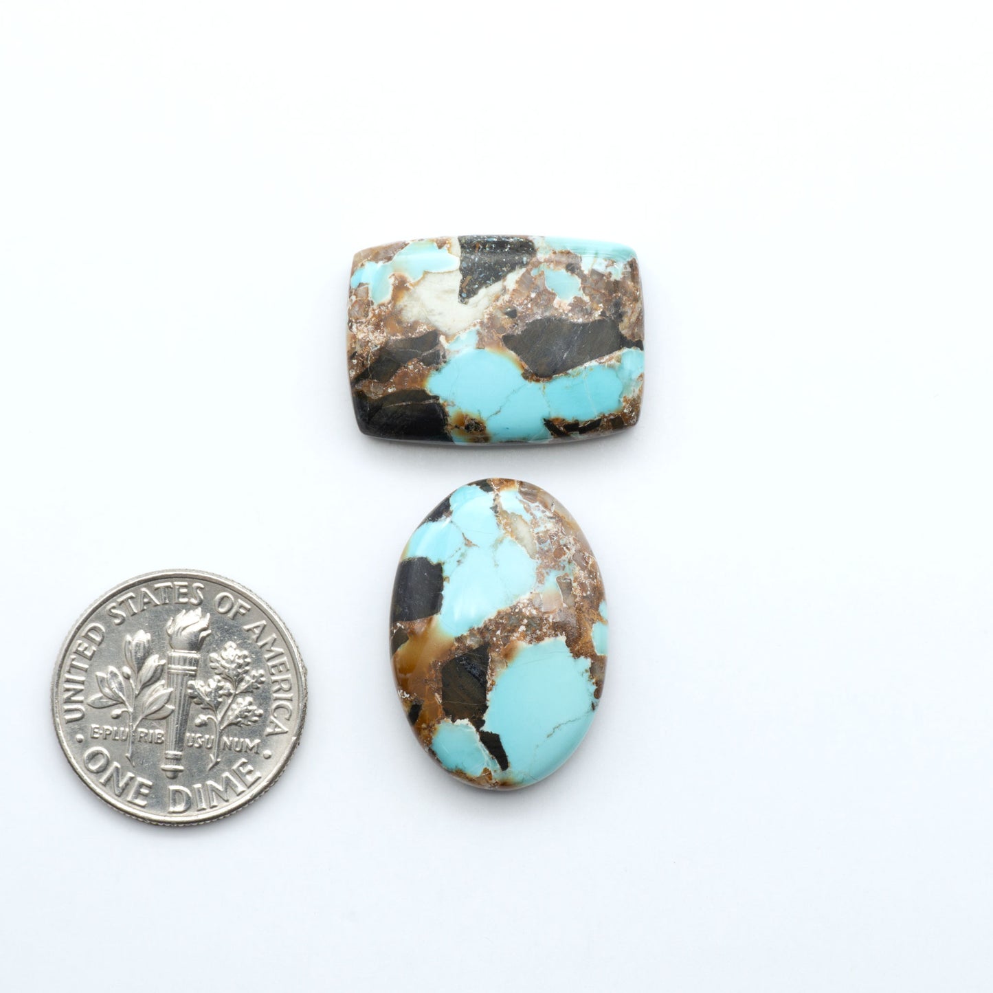 Black Jack turquoise cabochons, blue-green color with black matrix, polished stones on a white background with a US dime for scale