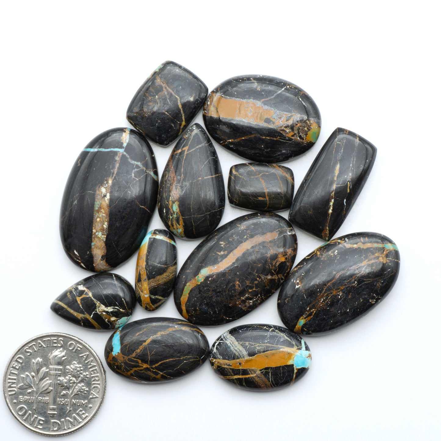 Black Jack turquoise cabochons, blue-green color with black matrix, polished stones on a white background with a US dime for scale
