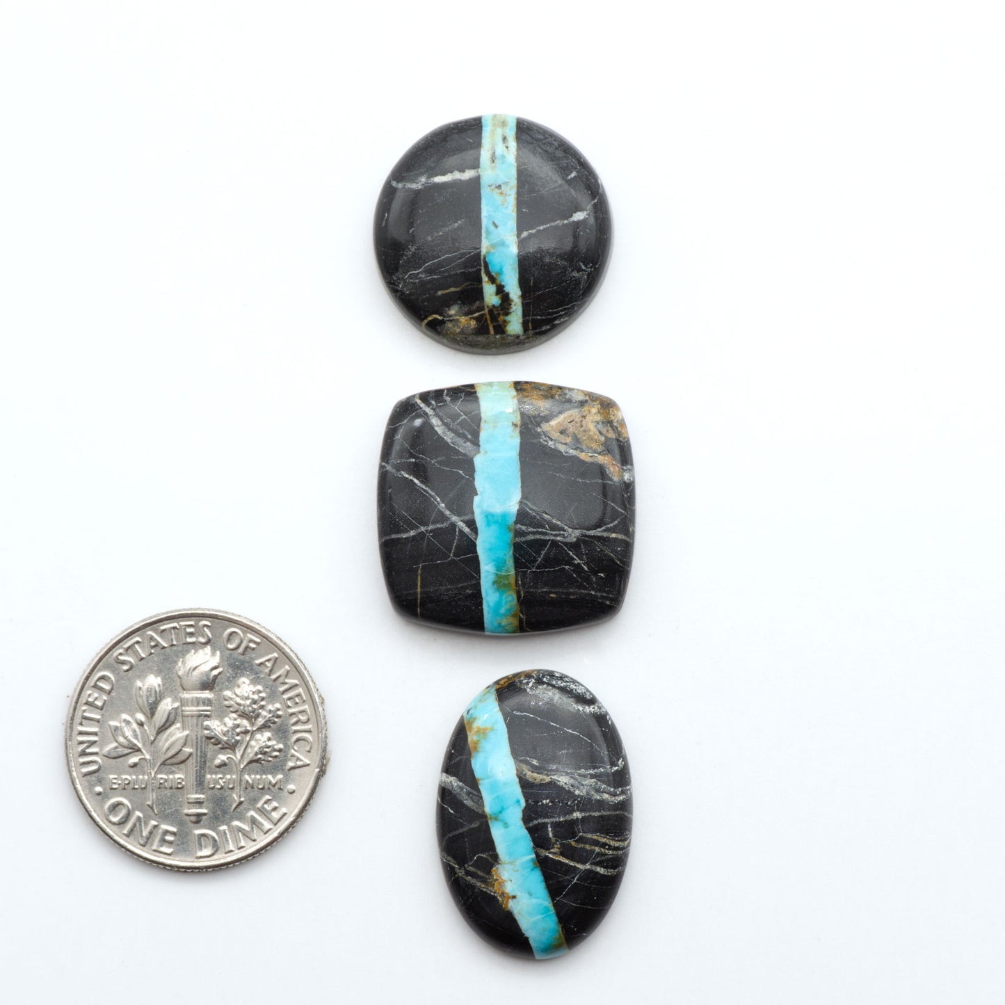 Black Jack turquoise cabochons, blue-green color with black matrix, polished stones on a white background with a US dime for scale