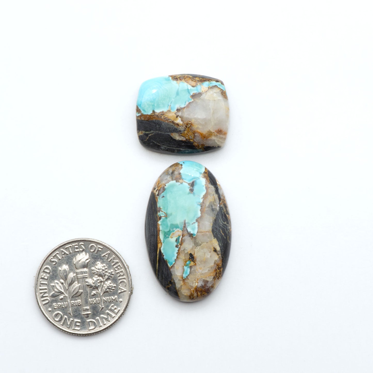 Black Jack turquoise cabochons, blue-green color with black matrix, polished stones on a white background with a US dime for scale