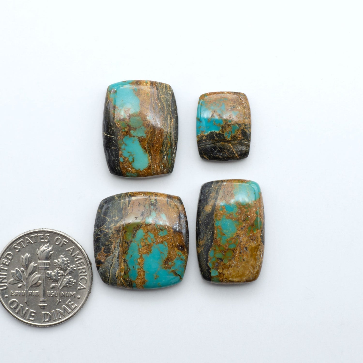 Black Jack turquoise cabochons, blue-green color with black matrix, polished stones on a white background with a US dime for scale
