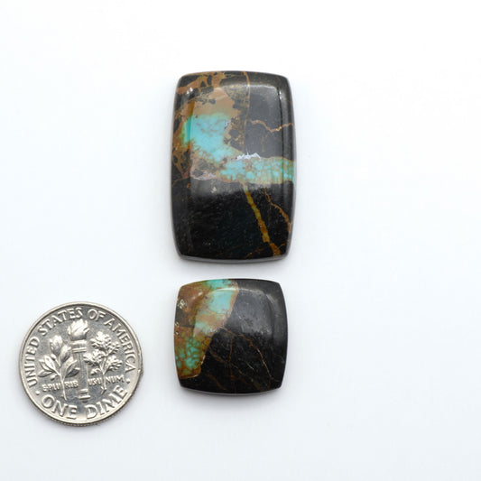 Two turquoise stone cabochons next to a U.S. dime on a white background