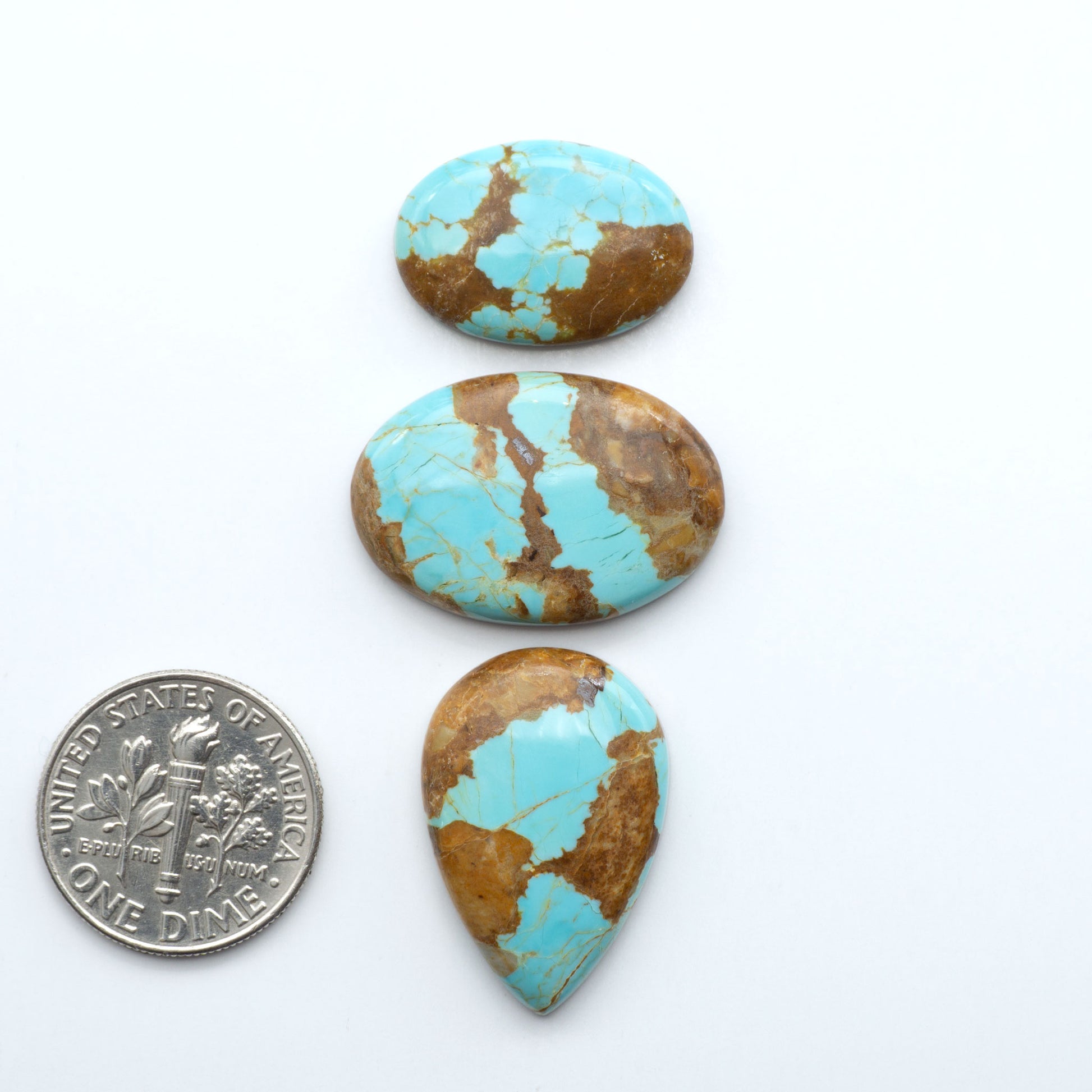 Three turquoise stones with brown accents next to a U.S. dime on a white background. Number 8 Turquoise Cabochons have been selected for their quality and unique appearance. Don't miss the chance to add a one-of-a-kind piece to your collection.