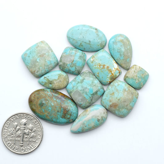 Turquoise stones with a U.S. dime coin for size comparison on a white background. Add a touch of beauty to your collection with our stunning Pilot Mountain Turquoise Cabochons. Perfect for jewelry making each piece is truly one-of-a-kind.