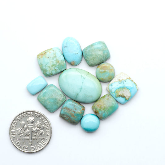 Turquoise stones with a U.S. dime for scale on a white background. Add a touch of beauty to your collection with our stunning Pilot Mountain Turquoise Cabochons. Perfect for jewelry making each piece is truly one-of-a-kind.