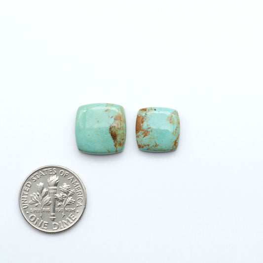 Turquoise stones with a U.S. dime for scale on a white background. Experience the beauty of Turquoise Mountain Cabochons. With their distinctive blue and green color, these gemstones are perfect for any jewelry piece.