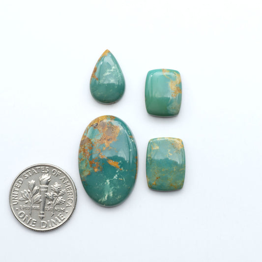 Turquoise stones with a U.S. dime for scale on a white background. Experience the beauty of Turquoise Mountain Cabochons. With their distinctive blue and green color, these gemstones are perfect for any jewelry piece.