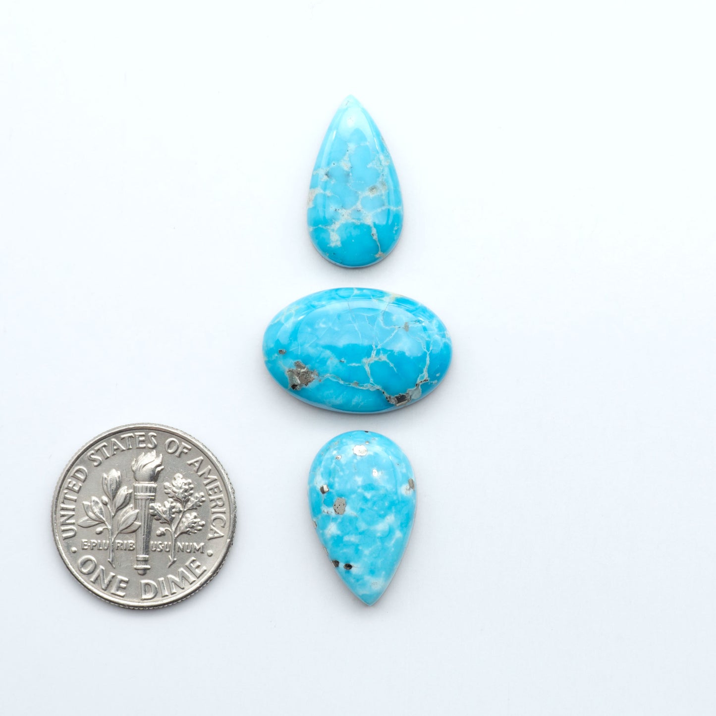 Three teardrop-shaped turquoise stones on a white background with a dime for scale. Sierra Bella Turquoise cabochons feature rich blue-green color and natural matrix variation. Ideal for silversmiths, jewelers, and custom jewelry designs