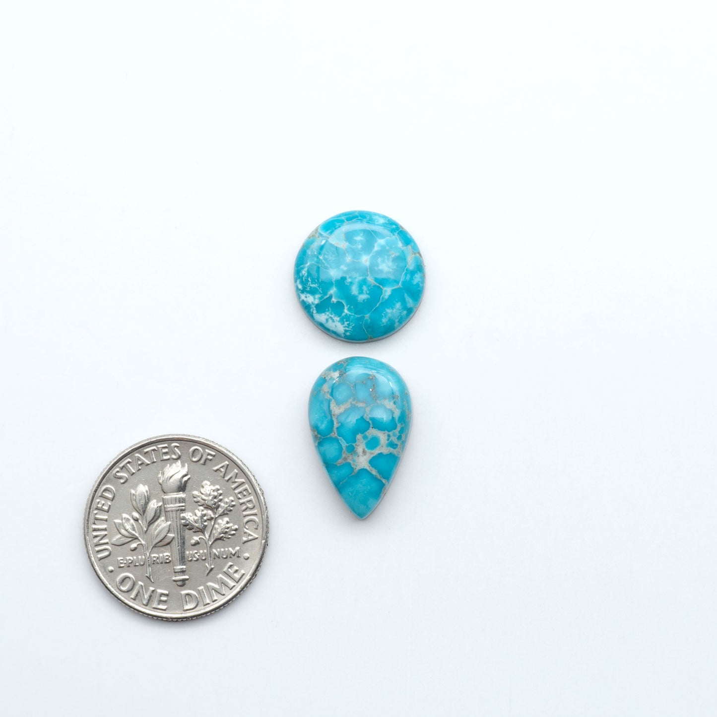 Two turquoise teardrop-shaped stones next to a U.S. dime on a white background. Sierra Bella Turquoise cabochons feature rich blue-green color and natural matrix variation. Ideal for silversmiths, jewelers, and custom jewelry designs