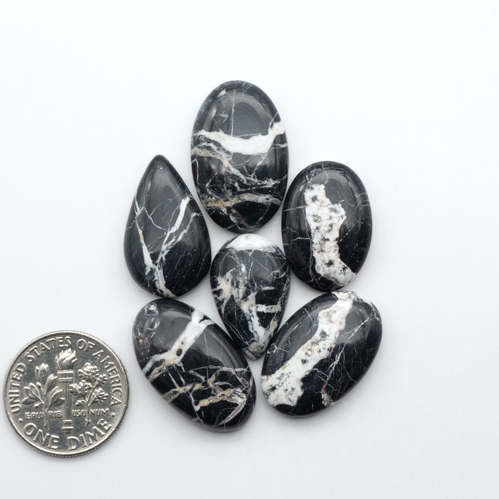 Black and white marbled stones with a quarter for scale on a white background.