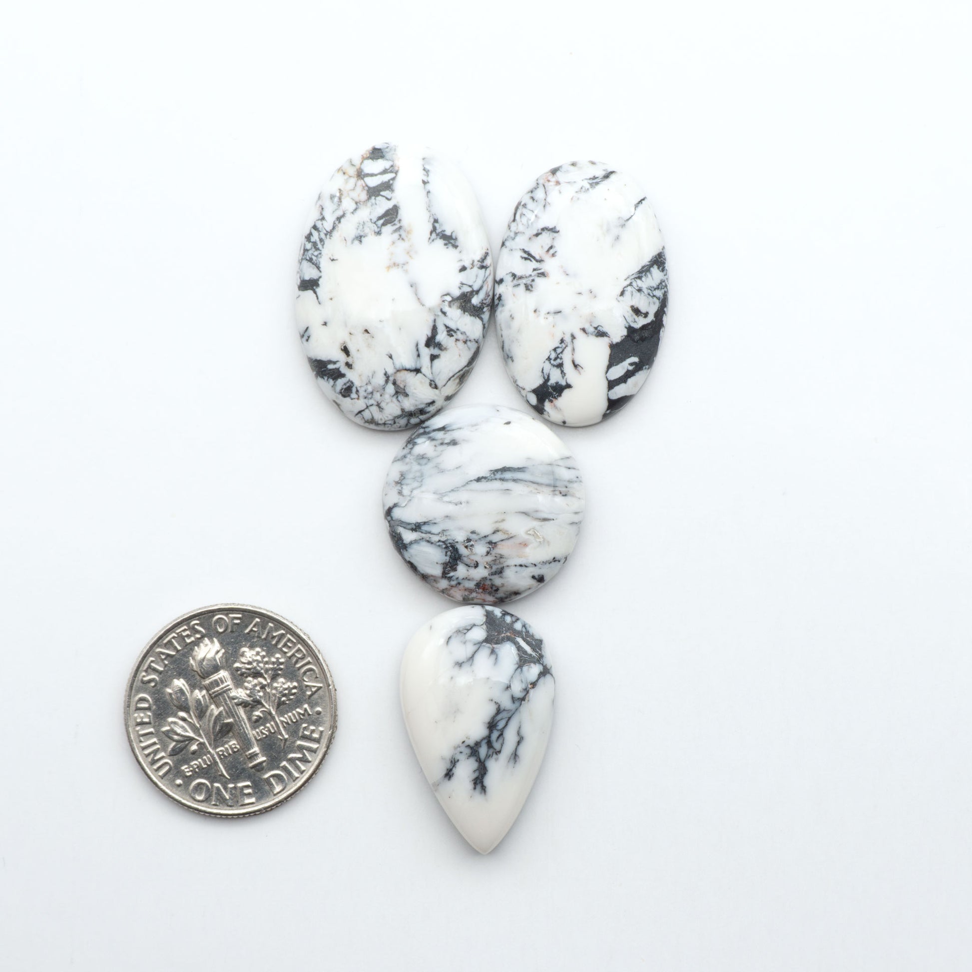 Marble-patterned stones with a U.S. dime for scale on a white background Natural White Buffalo Stone Cabochons are semi-precious gemstones cut into shapes ideal for jewelry-making, making them an excellent choice for artisans.