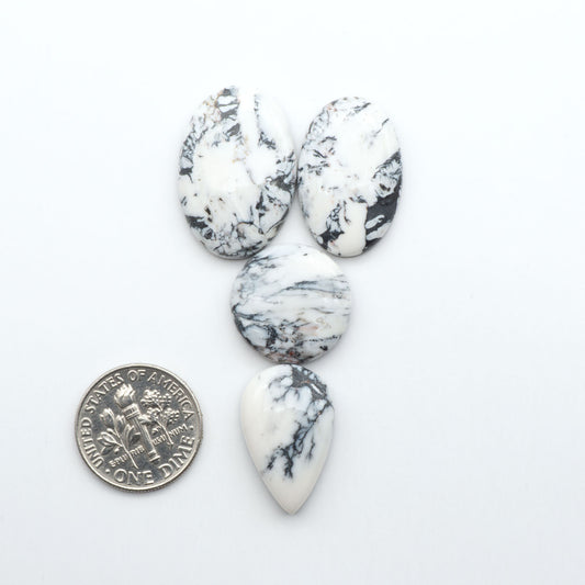 Marble-patterned stones with a U.S. dime for scale on a white background Natural White Buffalo Stone Cabochons are semi-precious gemstones cut into shapes ideal for jewelry-making, making them an excellent choice for artisans.