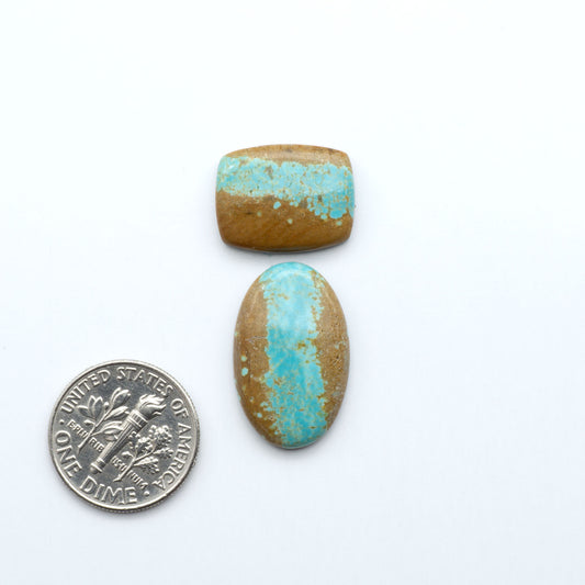 Two turquoise stones with gold accents next to a U.S. dime on a white background Number 8 Turquoise Cabochons have been selected for their quality and unique appearance. Don't miss the chance to add a one-of-a-kind piece to your collection.