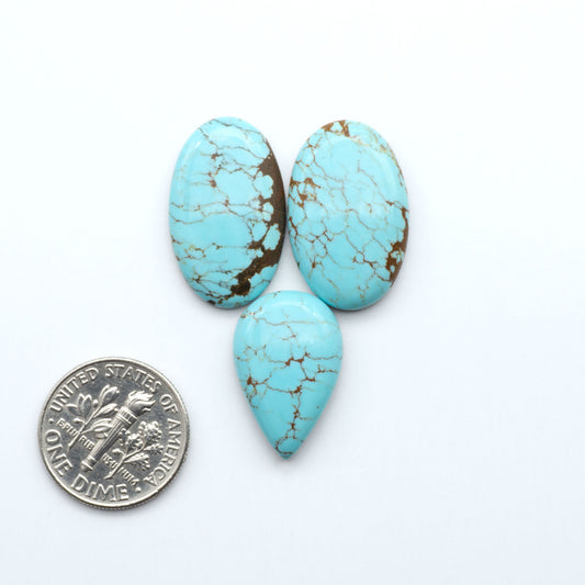 Three turquoise stones with a dime for scale on a white background Number 8 Turquoise Cabochons have been selected for their quality and unique appearance. Don't miss the chance to add a one-of-a-kind piece to your collection.