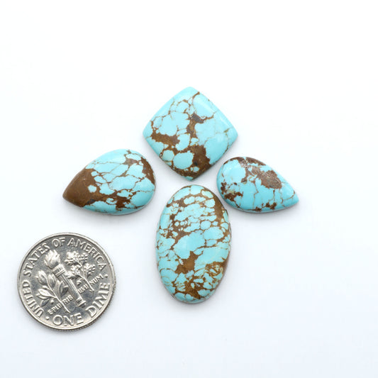 Turquoise stones with brown matrix on a white background, one next to a U.S. dime for size comparison. Number 8 Turquoise Cabochons have been selected for their quality and unique appearance. Don't miss the chance to add a one-of-a-kind piece to your collection.