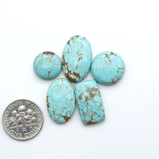 Turquoise stones with brown matrix next to a U.S. dime on a white background. Number 8 Turquoise Cabochons have been selected for their quality and unique appearance. Don't miss the chance to add a one-of-a-kind piece to your collection.