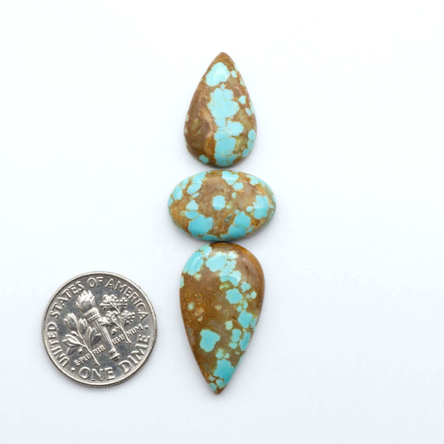 Turquoise stone with three teardrop shapes next to a U.S. dime for scale on a white background. Number 8 Turquoise Cabochons have been selected for their quality and unique appearance. Don't miss the chance to add a one-of-a-kind piece to your collection.