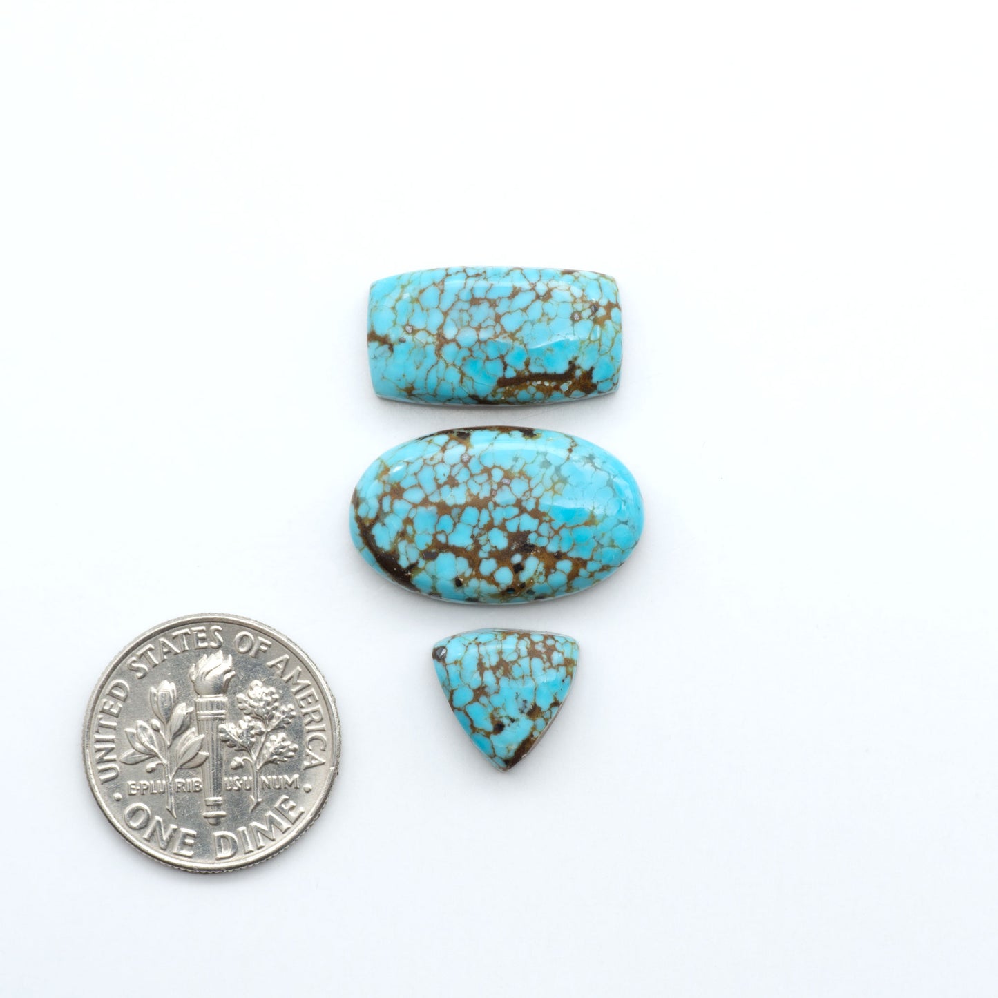Three turquoise stones of different shapes and sizes on a white background with a dime for scale. Number 8 Turquoise Cabochons have been selected for their quality and unique appearance. Don't miss the chance to add a one-of-a-kind piece to your collection.