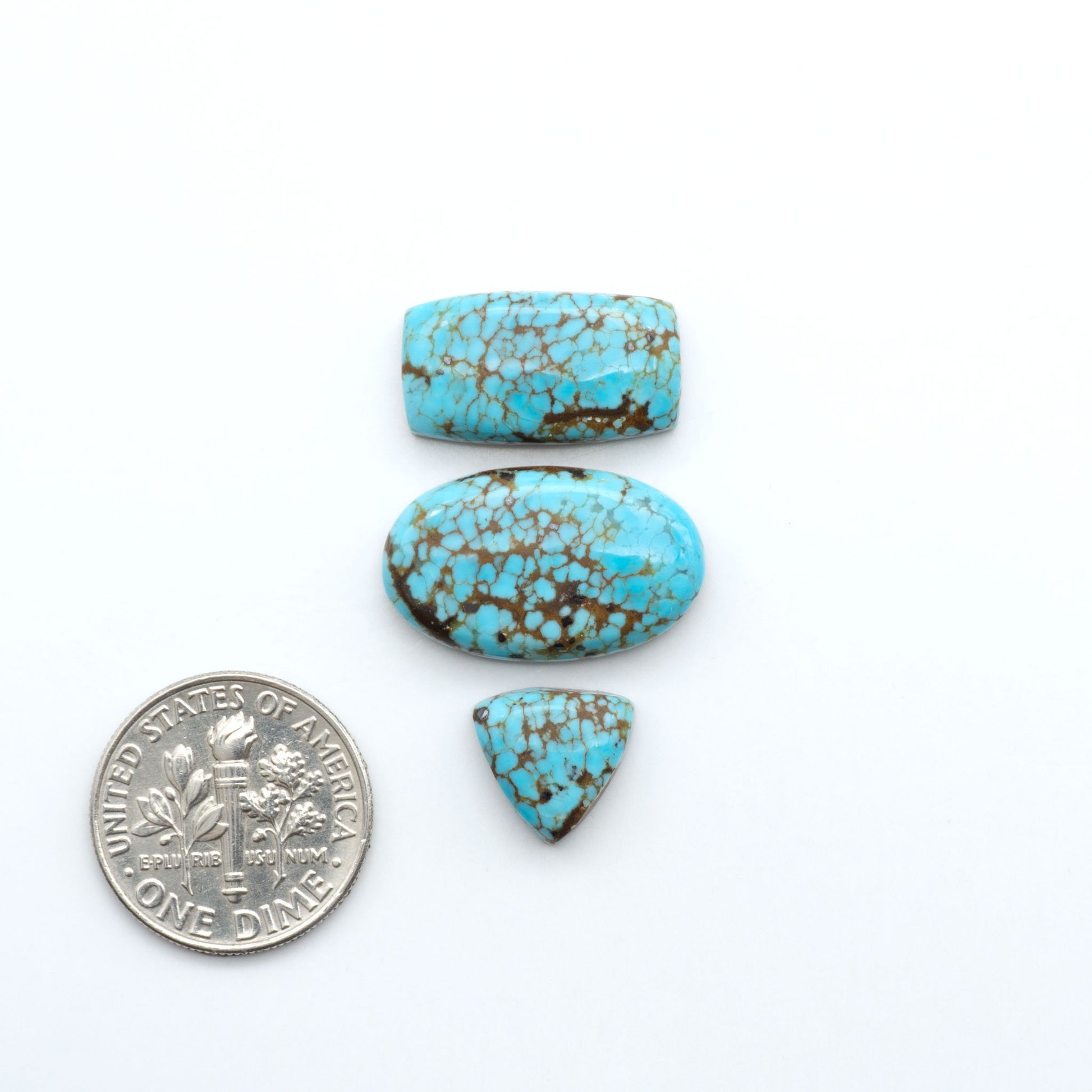 Three turquoise stones of different shapes and sizes on a white background with a dime for scale. Number 8 Turquoise Cabochons have been selected for their quality and unique appearance. Don't miss the chance to add a one-of-a-kind piece to your collection.