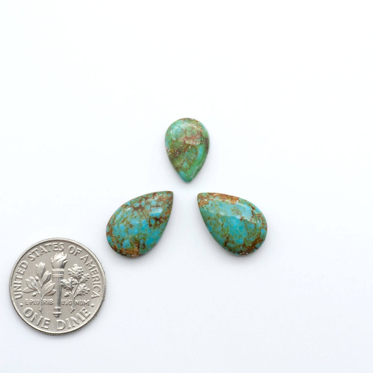 Three turquoise stones of different sizes next to a U.S. quarter coin on a white background. Number 8 Turquoise Cabochons have been selected for their quality and unique appearance. Don't miss the chance to add a one-of-a-kind piece to your collection.