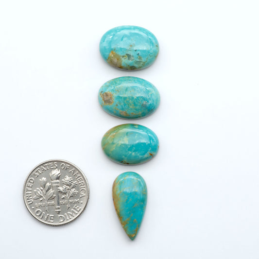 Four turquoise stones of different shapes and sizes on a white background with a dime for scale.