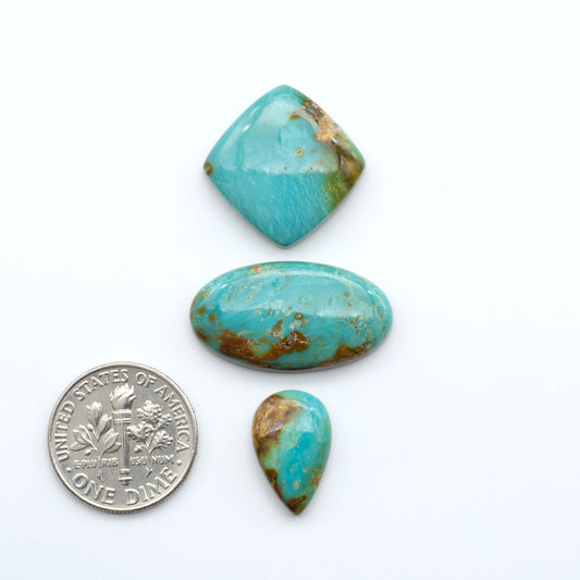 Three turquoise stones of different shapes and sizes on a white background with a dime for scale.