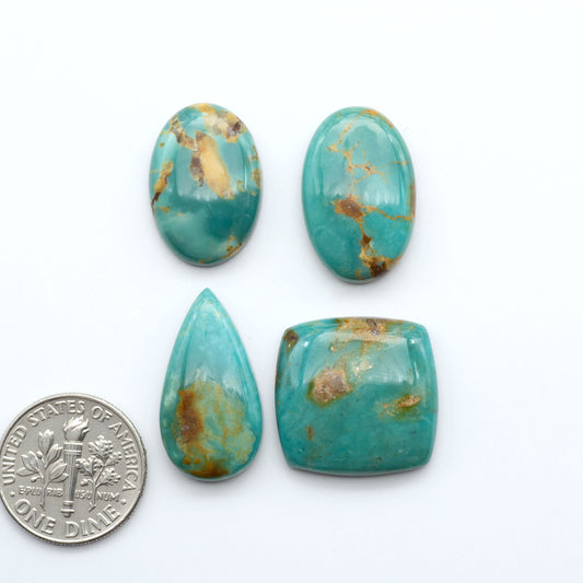 Four turquoise stones of different shapes and sizes on a white background with a dime for scale.