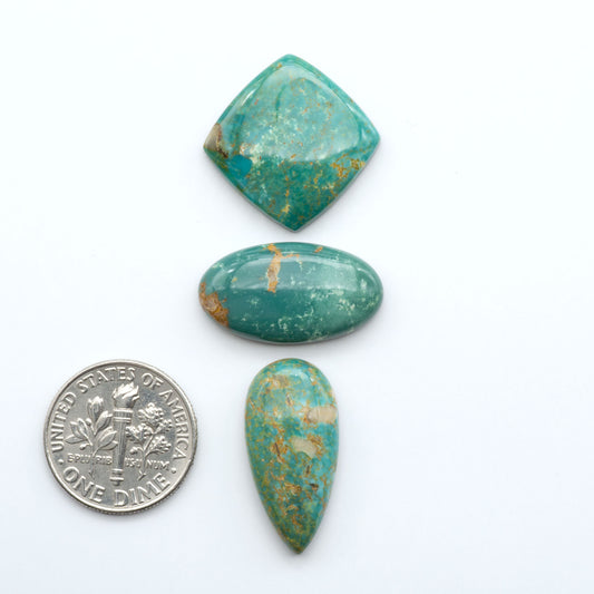 Three turquoise stones with gold veins on a white background, one next to a U.S. dime for size comparison.