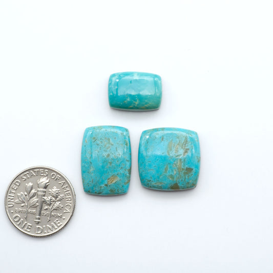 Three turquoise beads next to a U.S. dime on a white background