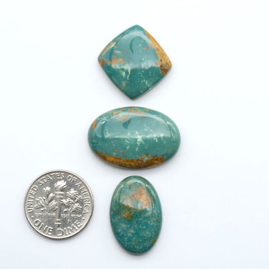 Three turquoise stones with gold veins on a white background, one next to a U.S. dime  for size comparison.