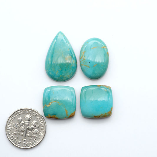 Four turquoise stones of different shapes and sizes on a white background with a dime  for scale.