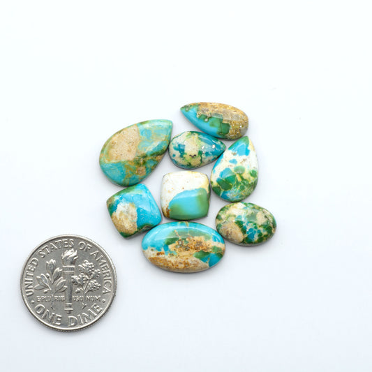 Turquoise with gold matrix stones with a U.S. dime for scale on a white background
