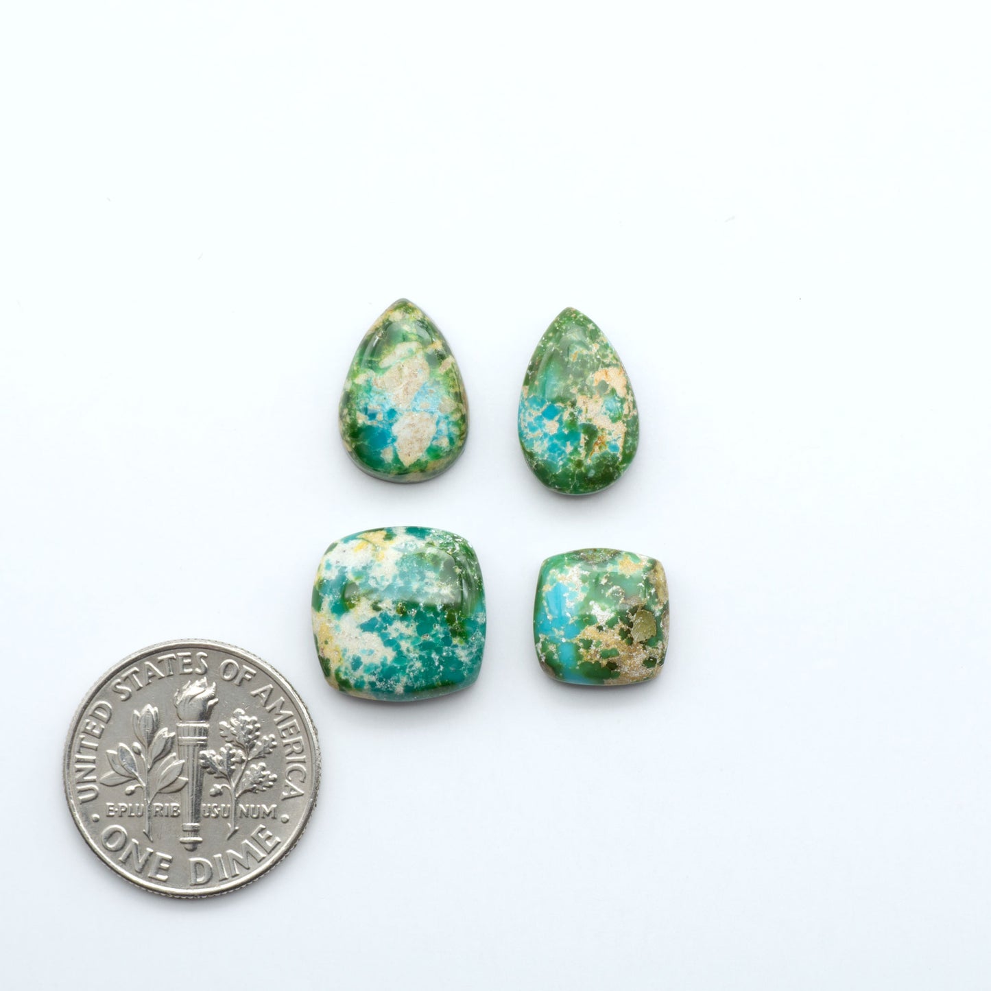 Four green and brown patterned stones with a dime for scale on a white background