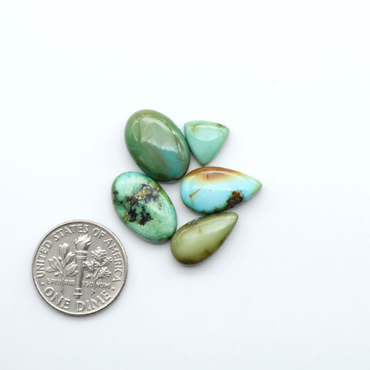 Turquoise stones with a U.S. dime coin on a white background