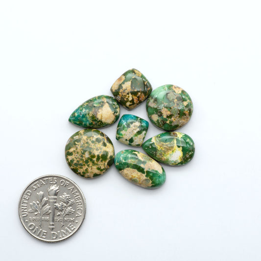 Green and gold marbled stones with a U.S. dime for scale on a white background