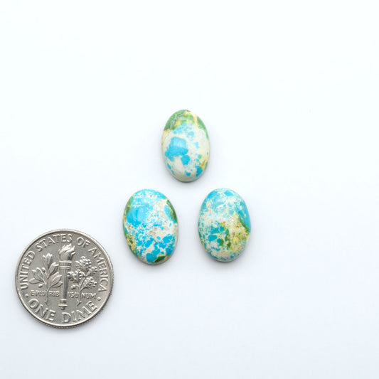 Three blue and green marbled stones next to a U.S. dime on a white background