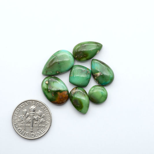 Green gemstones on a white background with a coin for scale