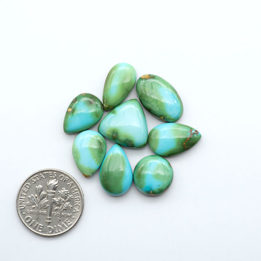 Turquoise stones with a U.S. dime for size comparison on a white background