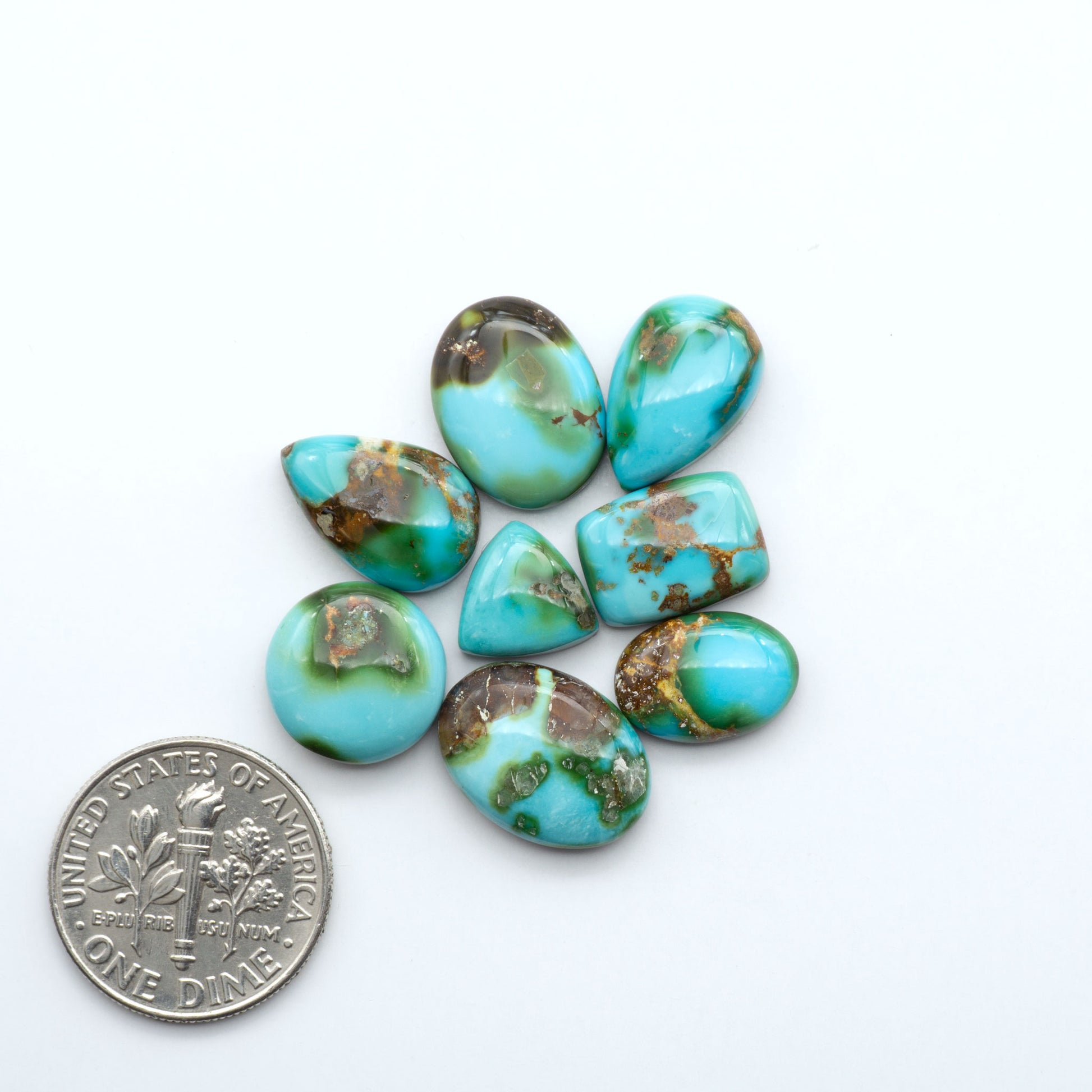 Turquoise stones with brown inclusions on a white background, shown with a dime for scale.