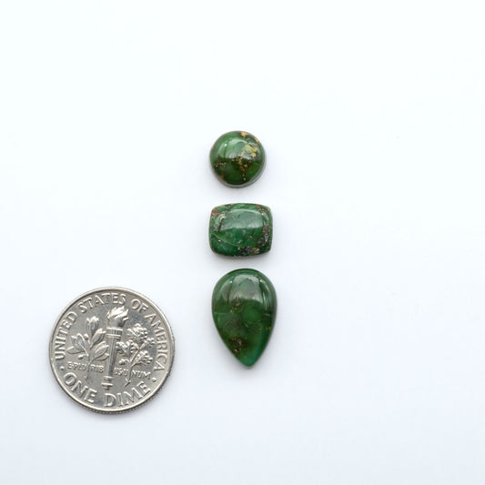 Three green stones of different sizes on a white background with a dime for scale.
