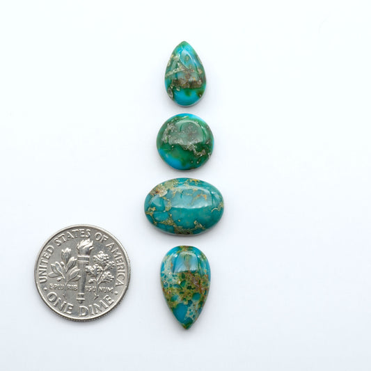 Four turquoise stones of varying sizes with a U.S. dime for scale on a white background