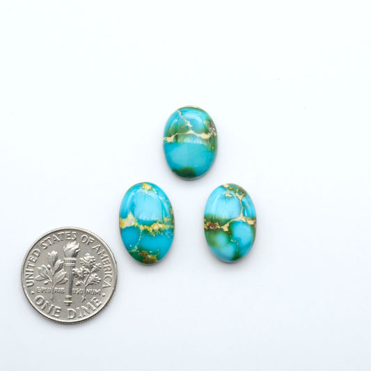 Turquoise stones with gold veins next to a U.S. dime on a white background