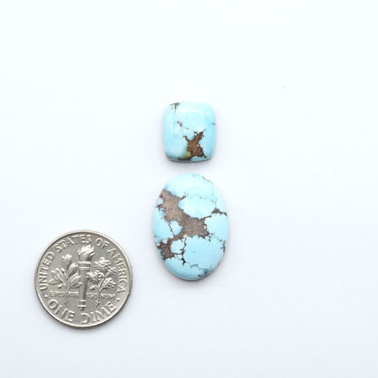 Two turquoise stones with brown matrix next to a U.S. dime on a white background