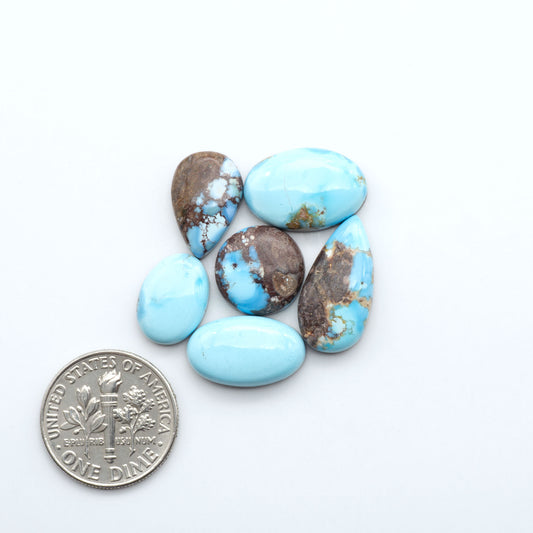 Turquoise stones with a dime for size comparison on a white background