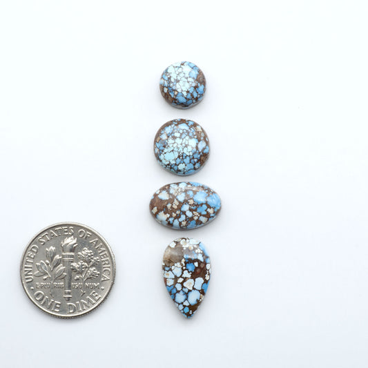 Four blue and brown marbled turquoise stones with a dime for scale on a white background