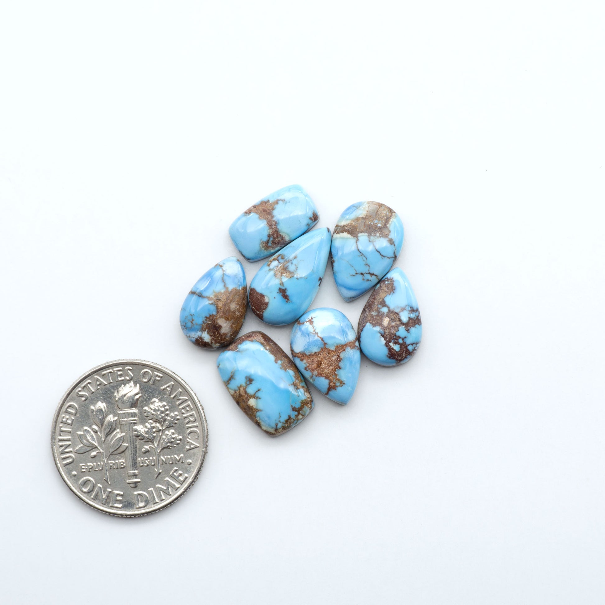 Turquoise stones with a dime for scale on a white background