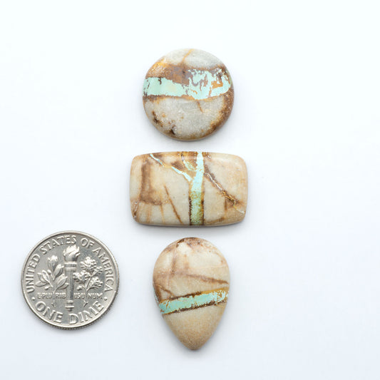 Royston Ribbon turquoise cabochons tan matrix with blue-green veins, three polished stones with U.S. dime for scale.
